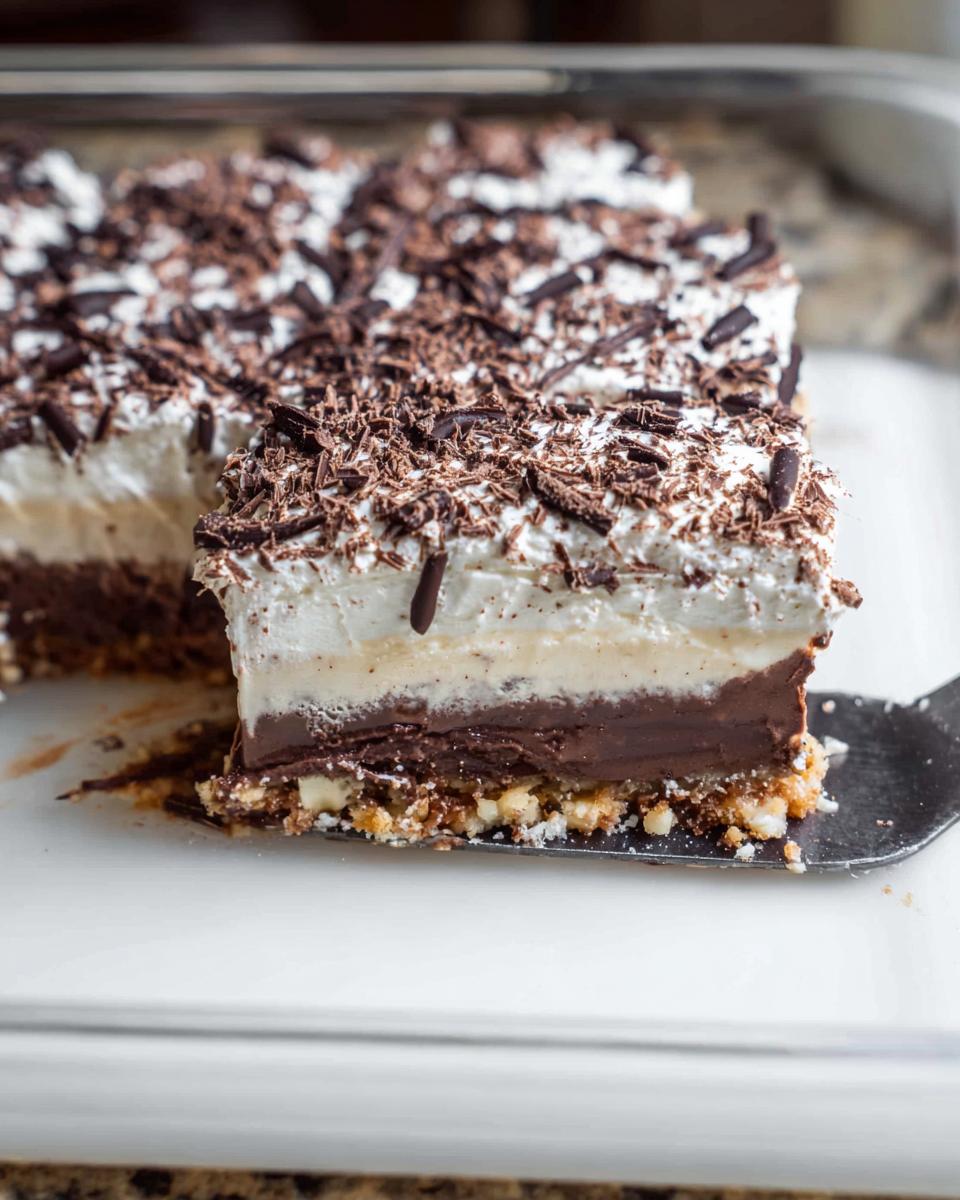 A slice of decadent chocolate layered Thanksgiving dessert, topped with whipped cream and chocolate shavings.