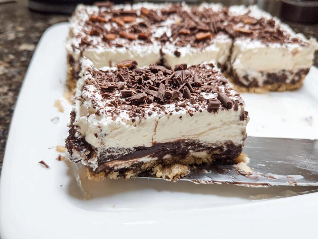 A slice of rich chocolate layered Thanksgiving dessert, topped with whipped cream and chocolate shavings.