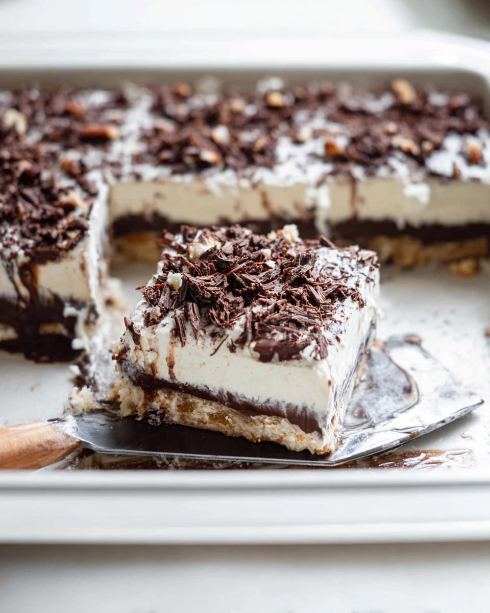 A slice of a rich chocolate layered Thanksgiving dessert, topped with whipped cream and chocolate shavings.