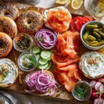 A vibrant breakfast platter featuring bagels, smoked salmon, cream cheese, capers, red onion, and fresh vegetables.