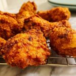 A close-up of perfectly fried chicken pieces, showcasing a crispy golden-brown exterior and juicy interior, embodying the Best Chicken 2025.