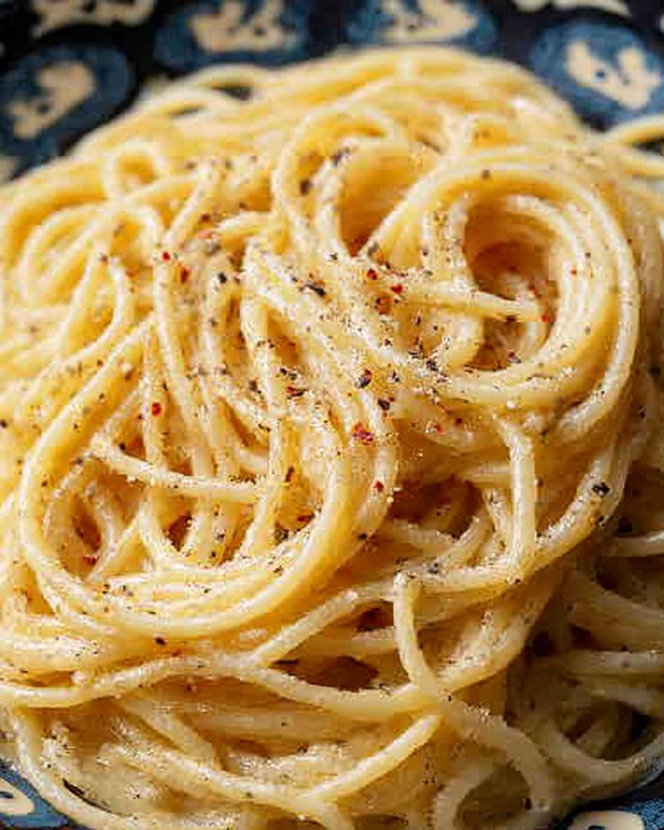 Close-up of a plate of Cacio e Pepe pasta, a simple yet delicious dinner idea, with visible black pepper.