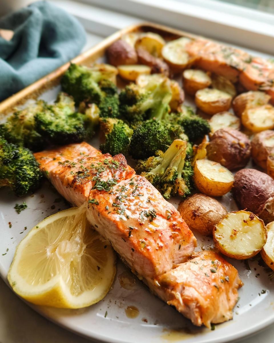 A close-up of a sheet pan meal featuring flaky salmon, roasted broccoli florets, and small red potatoes, a perfect easy dinner recipe.