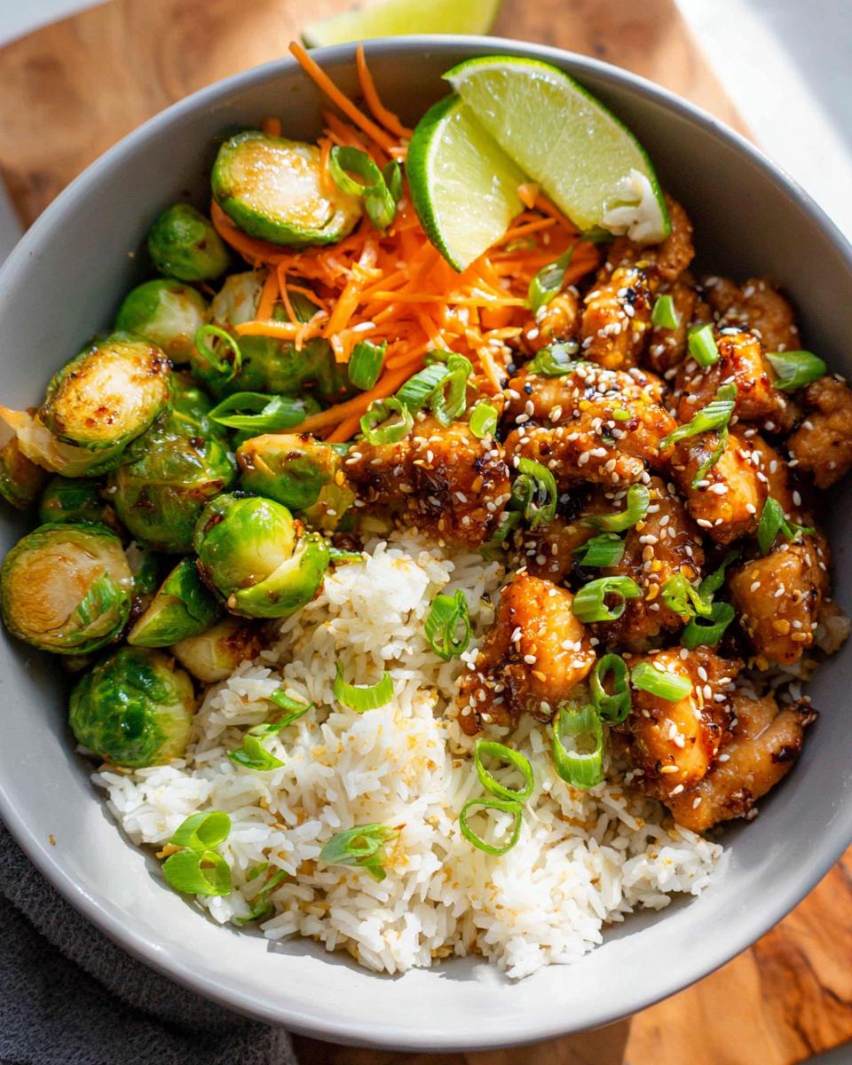 A healthy dinner idea: sesame chicken bowl with rice, roasted Brussels sprouts, shredded carrots, and lime.