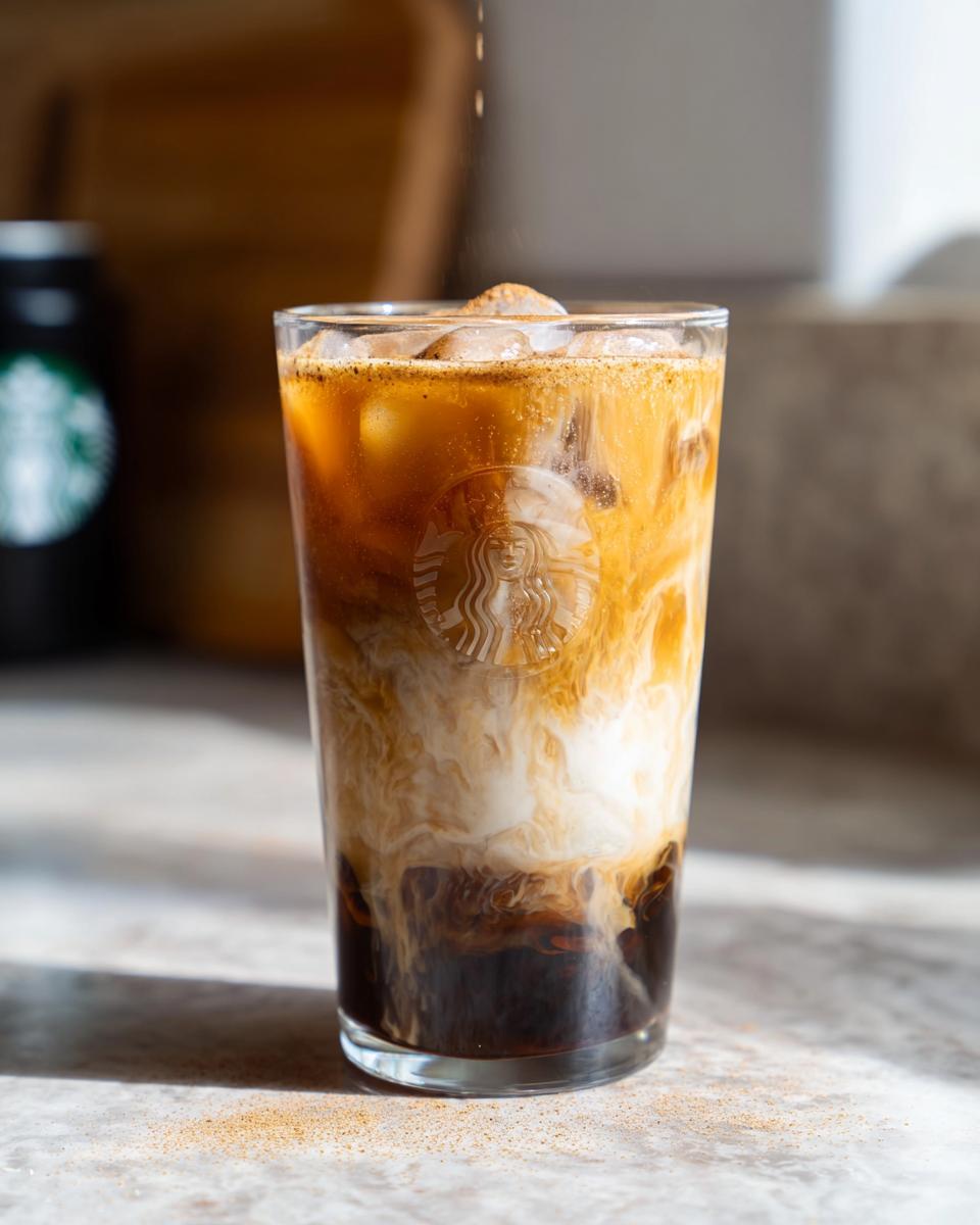 Close-up of an Iced Brown Sugar Oatmilk Shaken Espresso with ice, showing layers of dark coffee and white oatmilk.