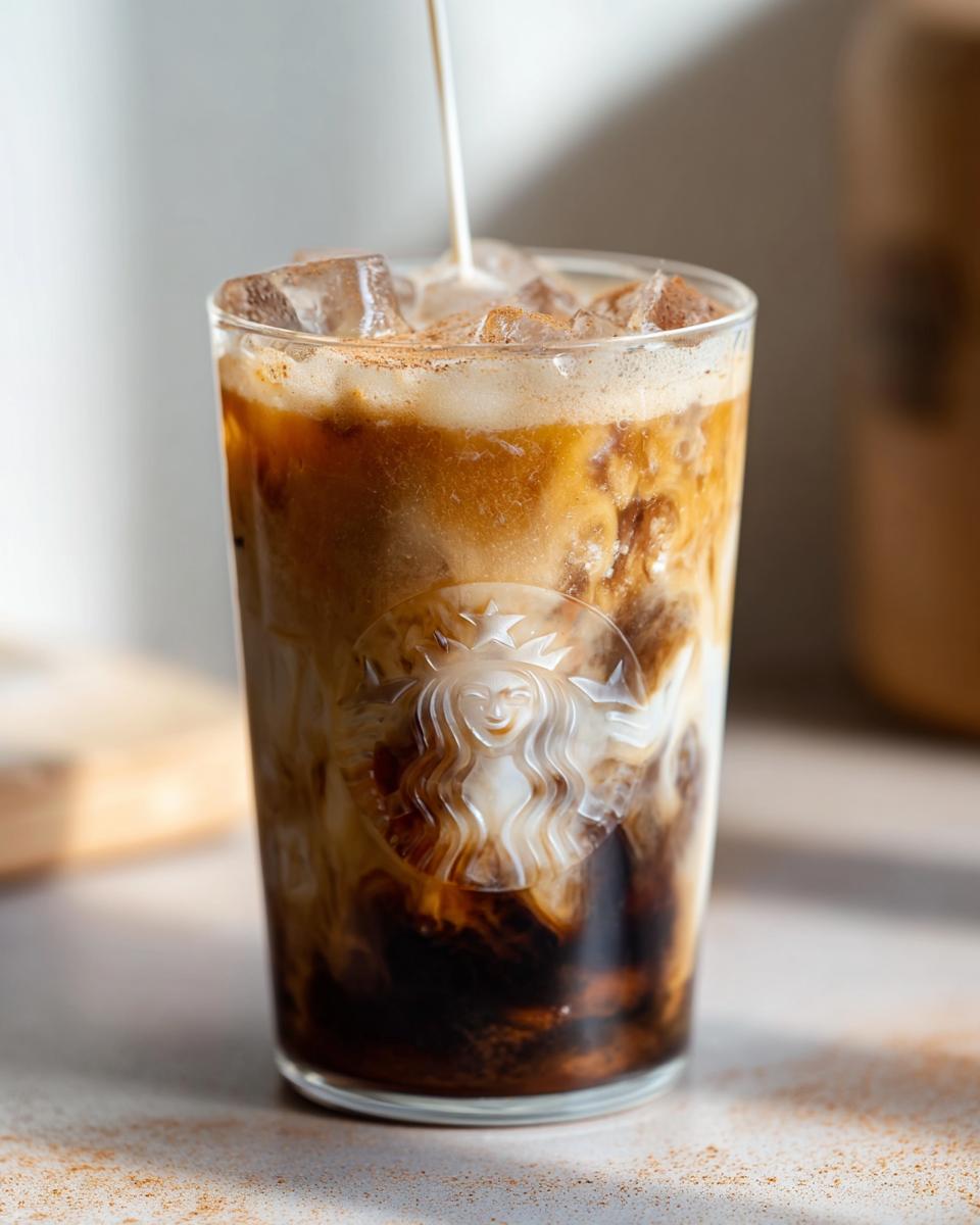 Oat milk being poured into a glass of Iced Brown Sugar Oatmilk Shaken Espresso over ice.