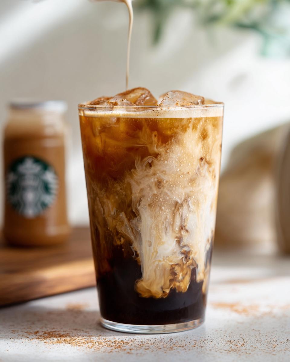 Close-up of oatmilk being poured into a glass of Iced Brown Sugar Oatmilk Shaken Espresso over ice.