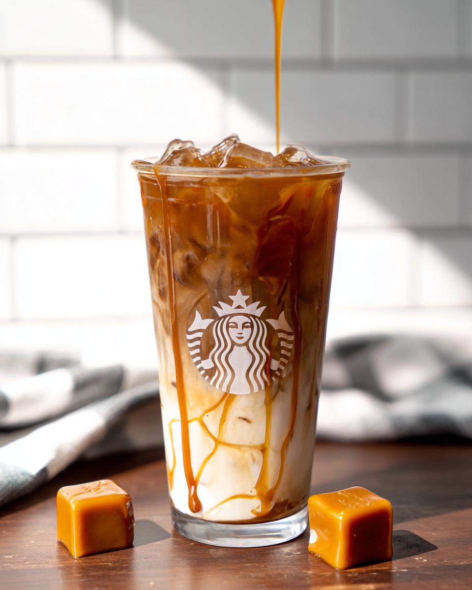 A tall glass of layered Café-Style Iced Caramel Macchiato copycat drink with ice, milk, and espresso, while caramel is being drizzled on top.