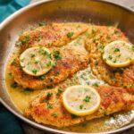 Four pan-seared chicken breasts in a lemon butter sauce, garnished with lemon slices and parsley. Perfect for dinner recipes for busy weeknights.
