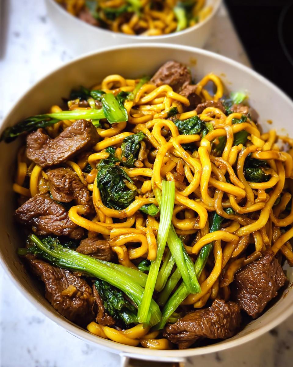 Close-up of a bowl filled with one-pan beef and broccoli noodles, showcasing tender beef strips and vibrant green vegetables.