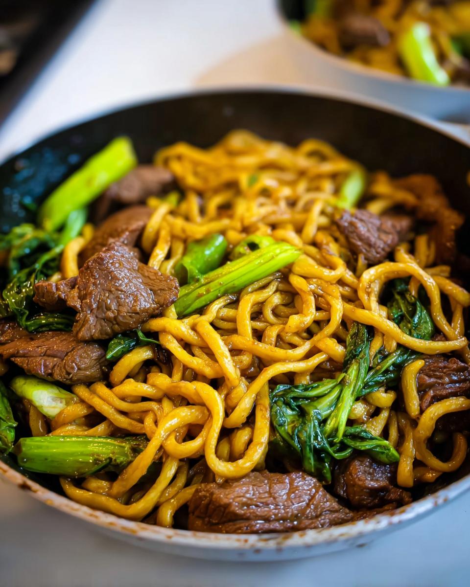 Close-up of a one-pan dinner with tender beef, yellow noodles, and green vegetables.