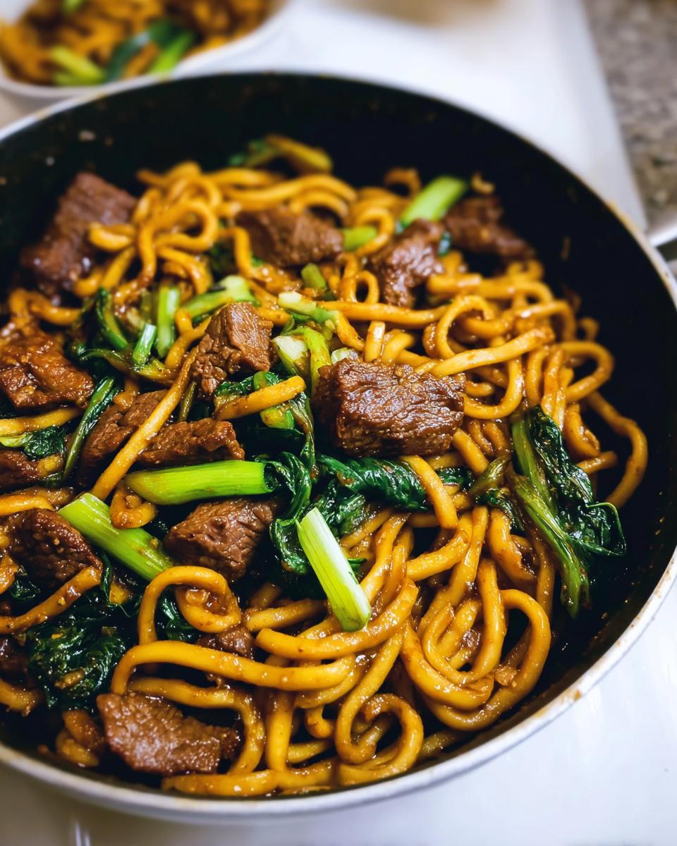 Close-up of a one-pan dinner with beef, noodles, and green vegetables in a skillet.