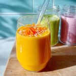 A vibrant orange smoothie in a glass, topped with shredded carrots and coconut, perfect for breakfast ideas in 20 minutes.