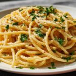 Close-up of a plate piled high with spaghetti, a classic pasta recipe everyone asks for, garnished with parsley and cheese.