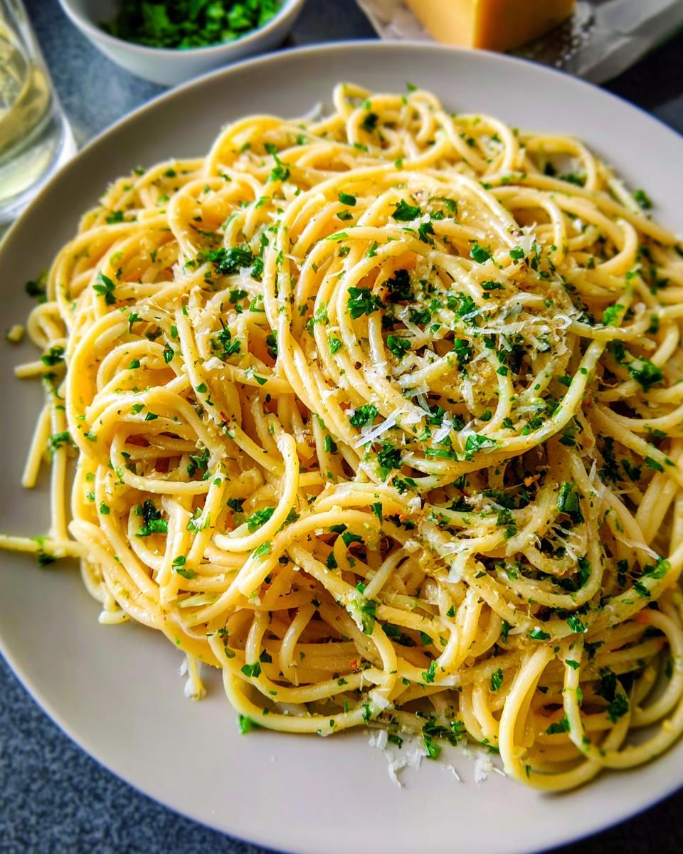 A close-up of a plate of garlic parmesan spaghetti, a quick pasta recipe in 20 minutes, garnished with fresh parsley and grated cheese.
