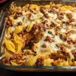 A close-up of a cheesy pasta bake with ground meat and shells, a perfect dinner recipe.