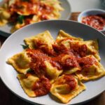 Close-up of perfect pasta recipes: ravioli generously topped with a rich red sauce.
