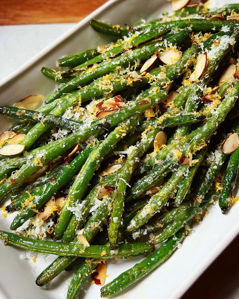 Close-up of perfect Thanksgiving green beans topped with slivered almonds, lemon zest, and grated cheese.