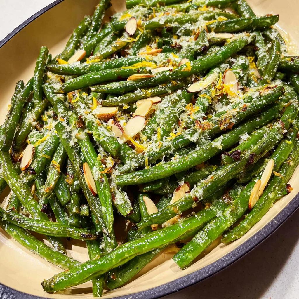 Close-up of perfect Thanksgiving green beans topped with sliced almonds, grated cheese, and lemon zest.