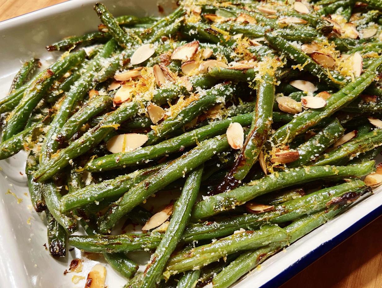 Close-up of perfectly cooked Thanksgiving green beans, topped with toasted almonds and lemon zest.
