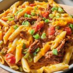 A bowl of penne pasta with shredded beef, tomatoes, cheese, and green onions, perfect for quick dinner recipes in 20 minutes.