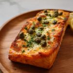 A perfectly cooked salmon fillet topped with capers and parsley, served with lemon slices, a perfect example of restaurant-style dinner recipes at home.