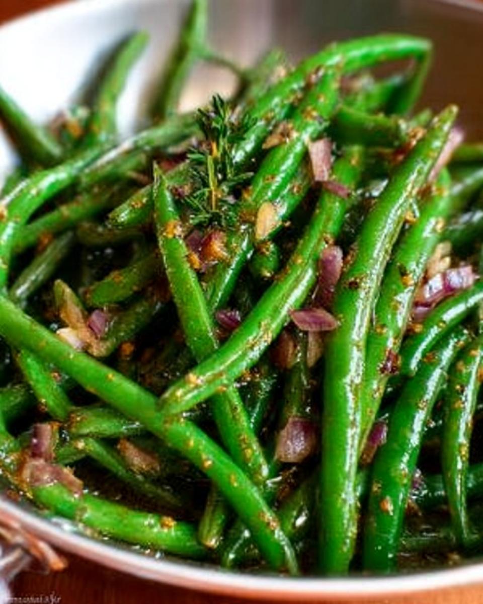 Close-up of vibrant green beans tossed with red onion, garlic, and herbs, ready for Thanksgiving.