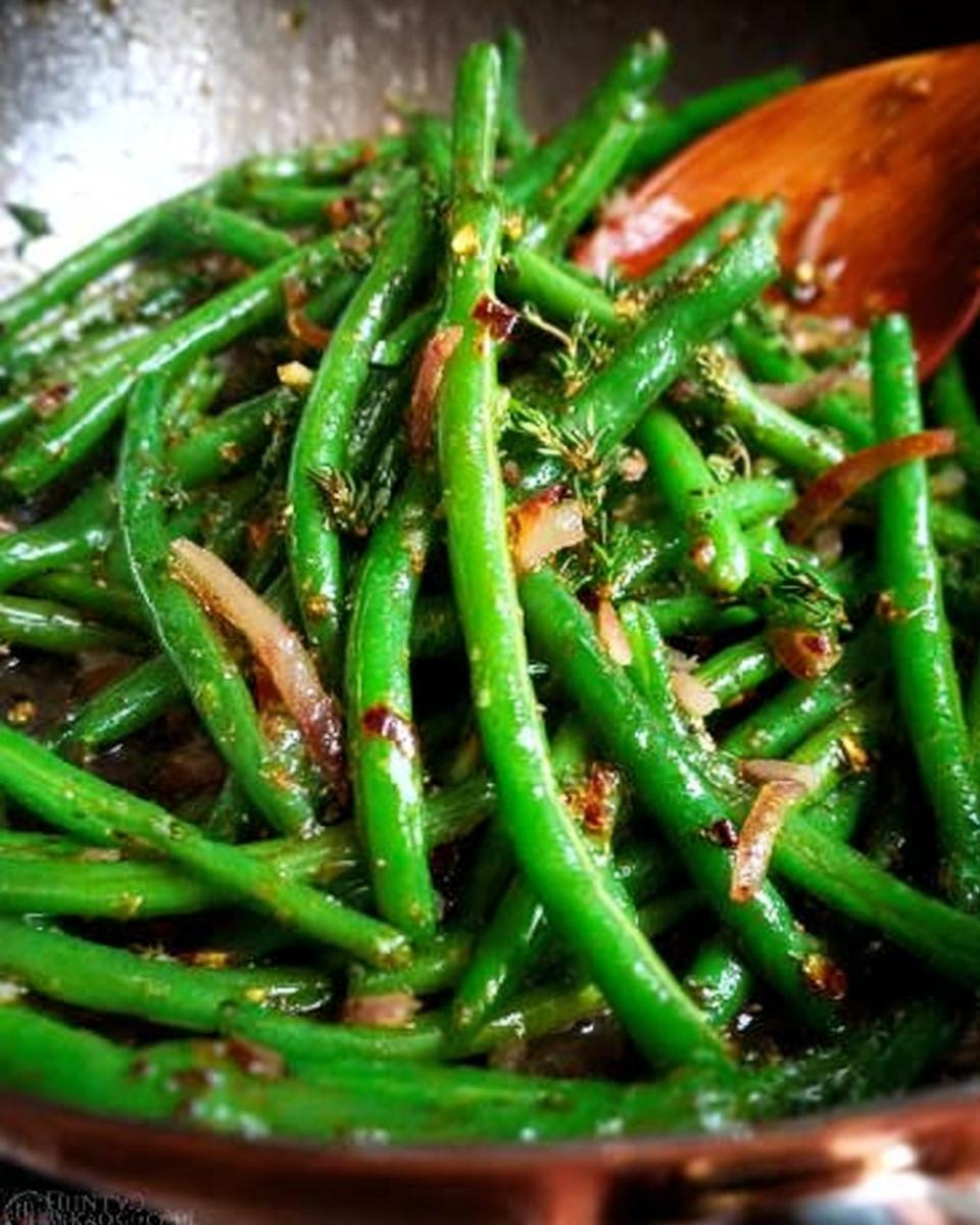 Close-up of vibrant green beans cooked with shallots and herbs, ready for a restaurant-style Thanksgiving meal.