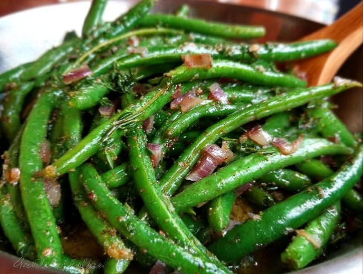Close-up of vibrant green beans tossed with red onion and herbs, ready for a restaurant-style Thanksgiving meal.