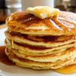 A tall stack of fluffy pancakes topped with butter and syrup, a perfect example of 5-Ingredient Breakfast Ideas.