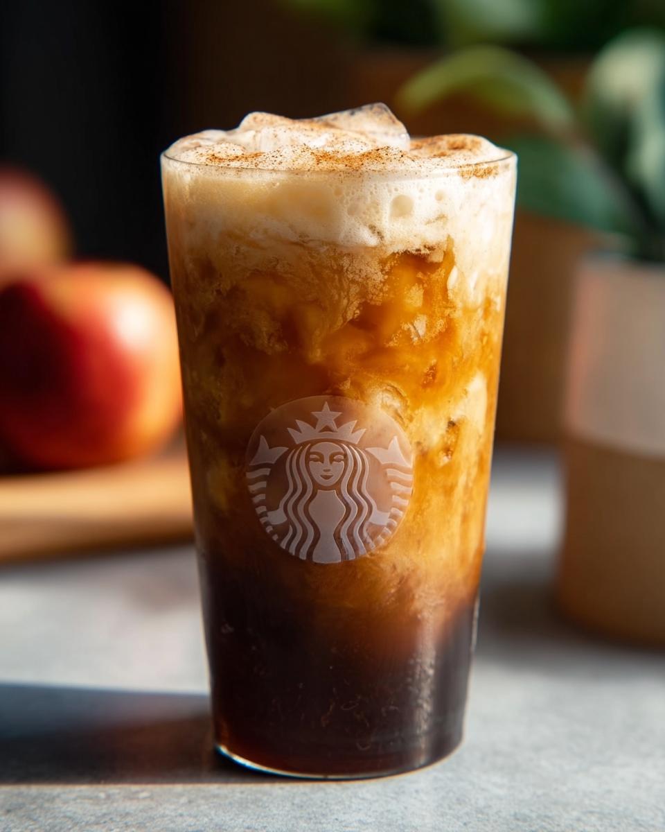 Close-up of an iced Apple Crisp Macchiato from Starbucks, with layered coffee, milk, foam, and cinnamon.