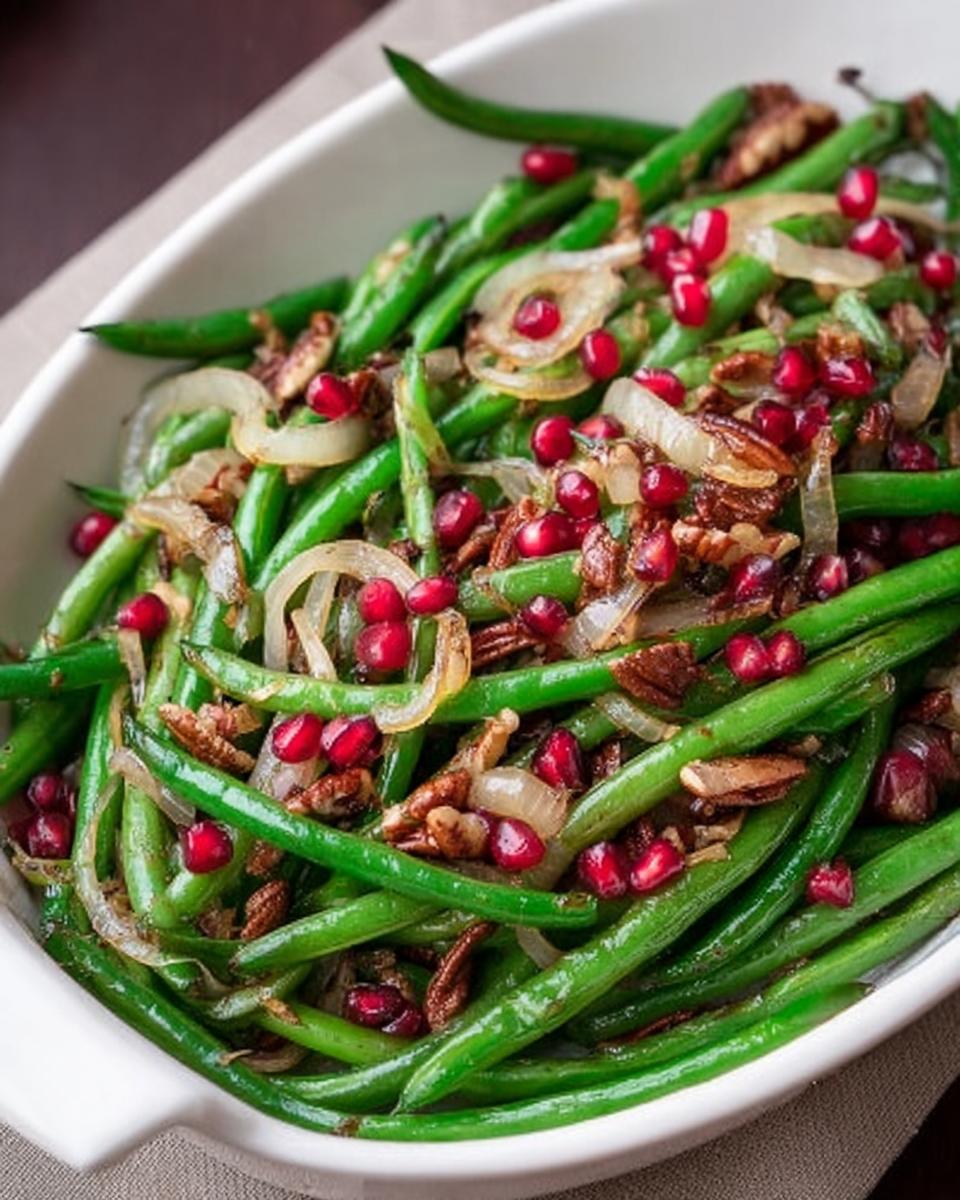 Close-up of Thanksgiving green beans dish with pomegranate seeds, pecans, and caramelized onions.
