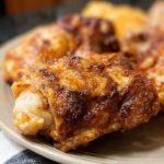 Close-up of perfectly cooked, crispy air fryer chicken thighs on a plate.