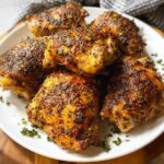 A plate of perfectly baked chicken thigh recipes, seasoned with herbs and spices.