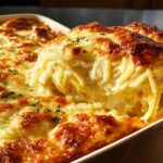 A scoop of creamy baked spaghetti casserole with a golden-brown cheesy crust, garnished with parsley. The Only Pasta Recipes Recipe You’ll Need.