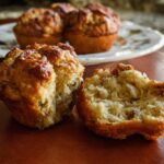 Close-up of a delicious stuffing muffin, one broken in half to show its fluffy interior, part of a batch of stuffing muffins.