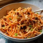 A bowl of shredded carrot salad with raisins and green onions, part of quick veggie sides recipes.