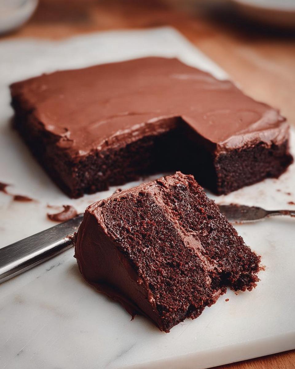 A slice of rich chocolate cake with decadent frosting, showcasing moist crumb and delicious cake ideas recipes.