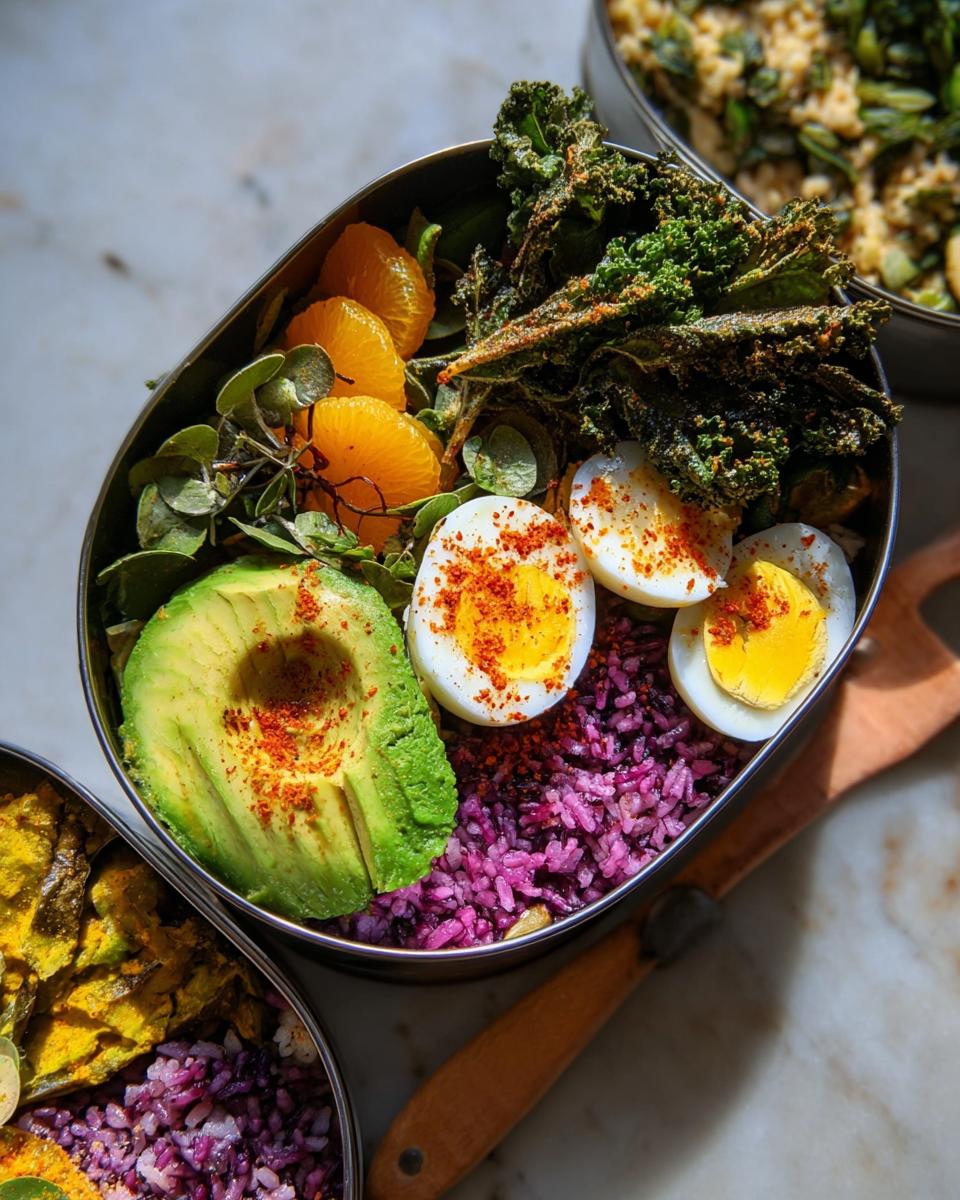 A vibrant bento box featuring hard-boiled eggs, avocado, orange slices, and purple rice, part of The Ultimate Egg Recipes Guide.