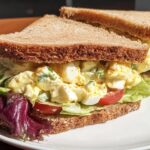 A delicious egg salad sandwich with whole wheat bread, lettuce, tomato, and a creamy egg filling, perfect for restaurant-style sandwich ideas.