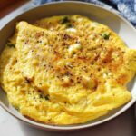 A close-up of a fluffy, golden-yellow omelette seasoned with black pepper, part of The Only Egg Recipes Recipe You’ll Need.