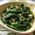 A close-up of a bowl filled with sautéed spinach, garlic, and red pepper flakes, part of the 20-Ingredient Veggie Sides Recipes.