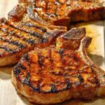Close-up of juicy, grilled pork chops with grill marks and a glaze, ready to be served.