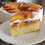 A slice of delicious peach cake with whipped cream and fresh peach slices on top, part of The Ultimate Cake Ideas Recipes Guide for Beginners.