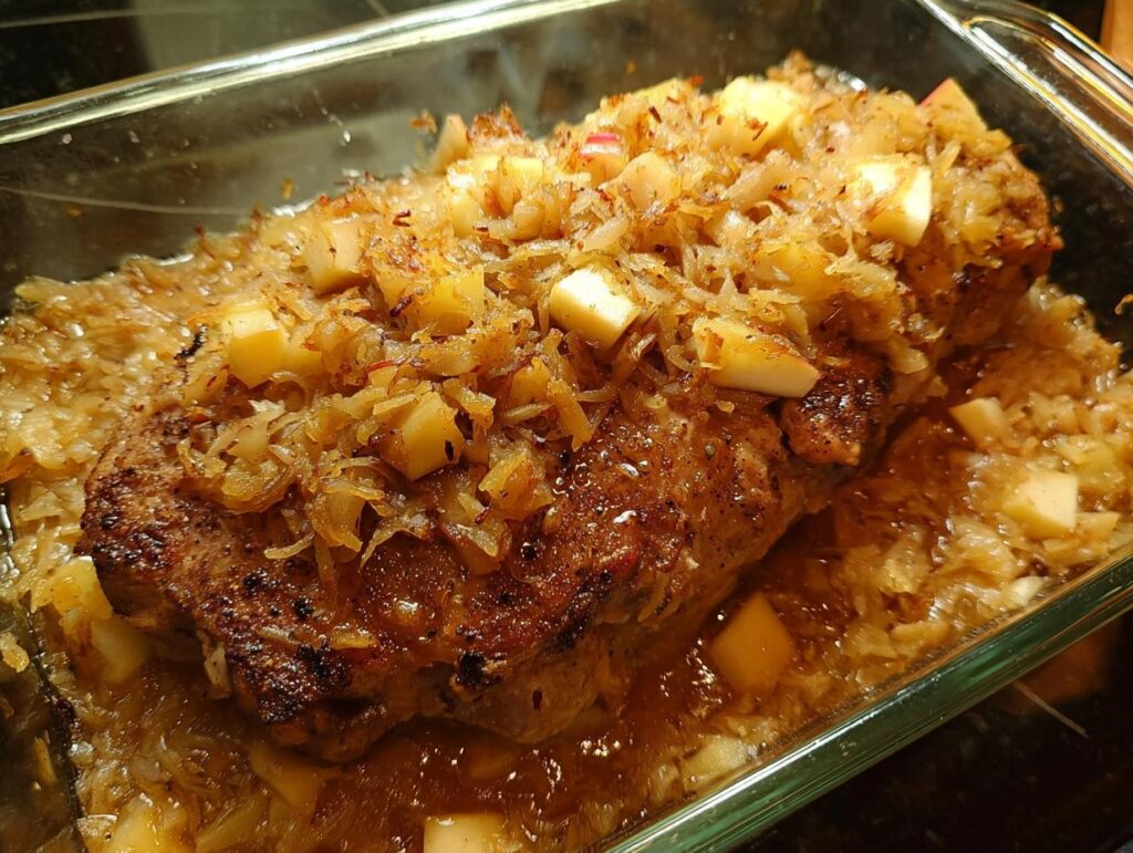 Close-up of a juicy pork chop baked with apples and onions in a glass dish, part of our 10-minute pork chops recipes.
