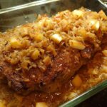 Close-up of a juicy pork chop baked with apples and onions in a glass dish, part of our 10-minute pork chops recipes.