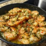 Close-up of a pan filled with glistening garlic butter shrimp, seasoned with herbs, perfect for restaurant-style shrimp recipes at home.