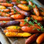 A close-up of roasted rainbow carrots, glazed and sprinkled with fresh thyme, perfect for veggie sides meal prep.