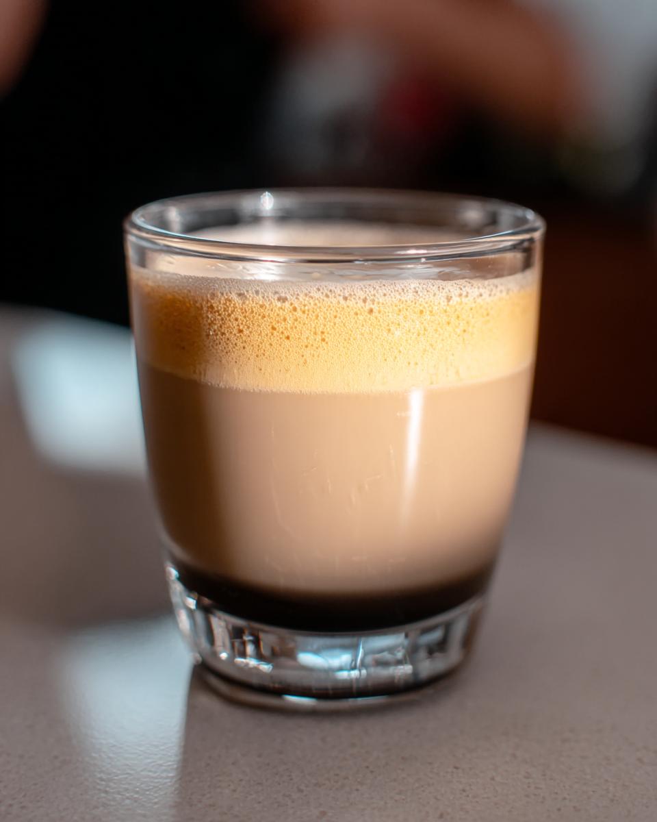 Close-up of a layered Starbucks drink with foamy top in a clear glass, perfect for busy weeknights.
