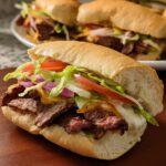 Close-up of a juicy steak sandwich with lettuce, tomato, onion, and cheese, part of 7-Ingredient Sandwich Ideas Recipes.